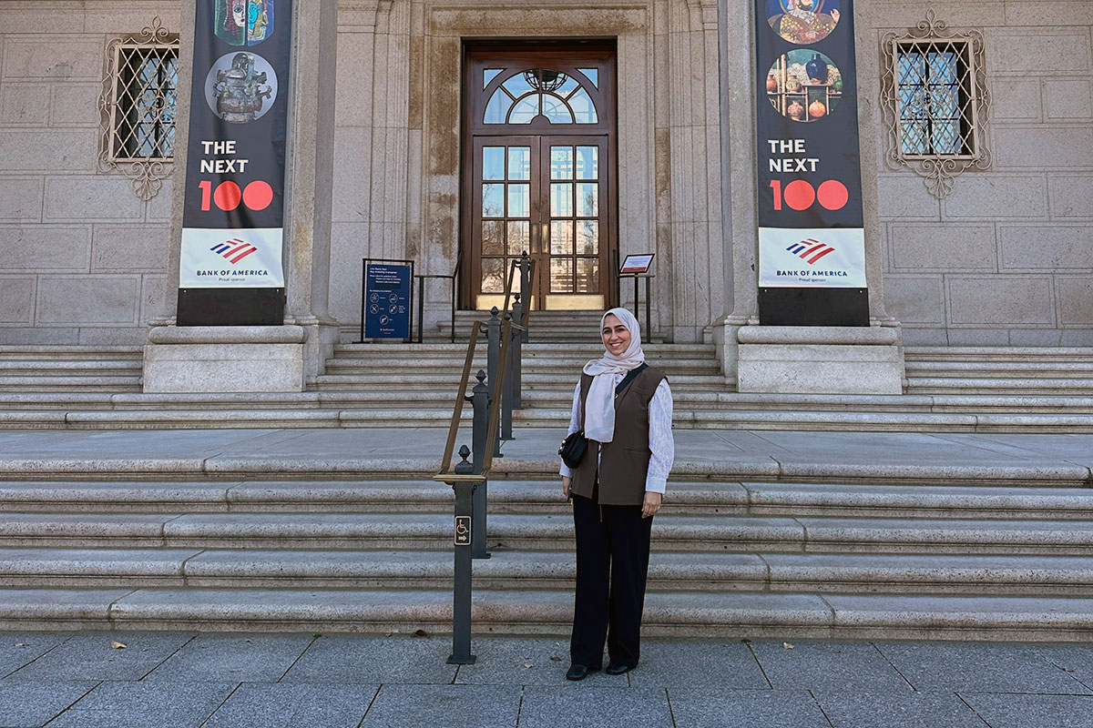 A woman poses at the steps of a museum.