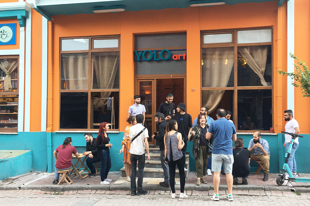 A crowd of people stand outside a bright orange building.