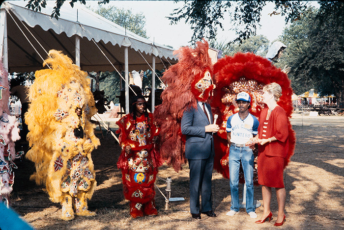 A reporter tries on the elaborate dress of the Mardi Gras Indians during an interview at the 1985 Folklife Festival. Photo by Jeff Tinsley, Ralph Rinzler Folklife Archives