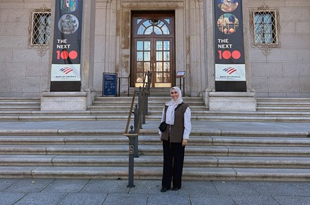 A woman poses at the steps of a museum.