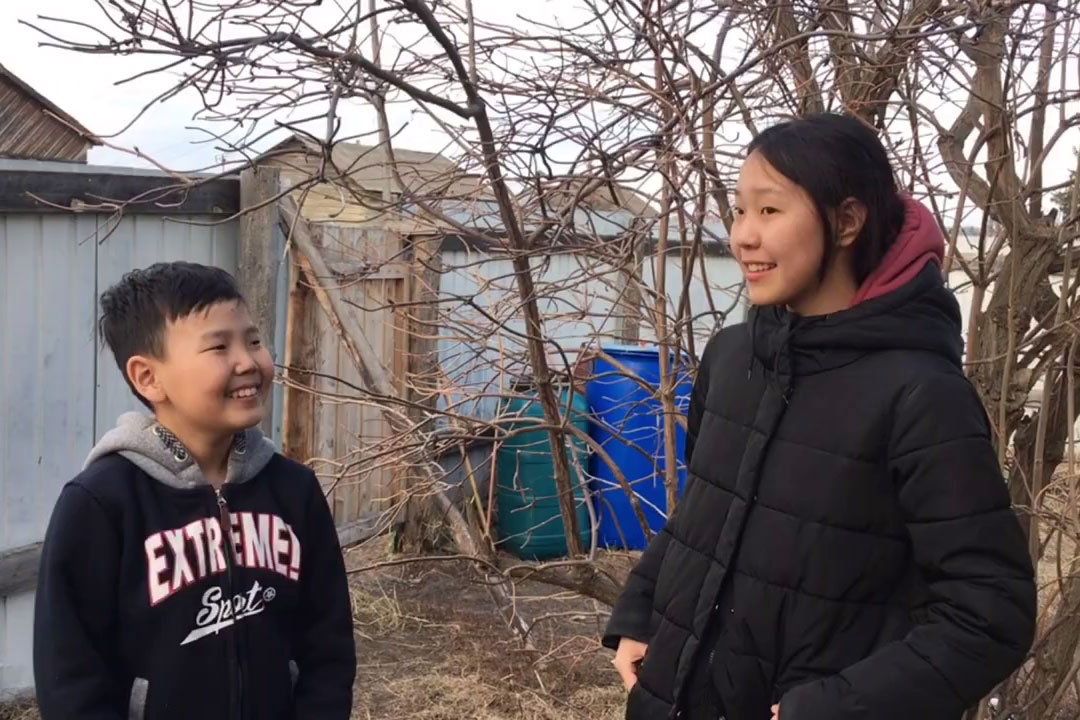 A screenshot of a YouTube video depicts a boy interviewing a girl outdoors in cold weather.