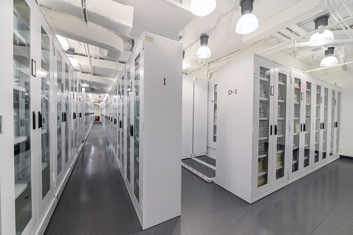 Rows of white shelving with glass cabinet doors, marked by rows with letters and numbers.