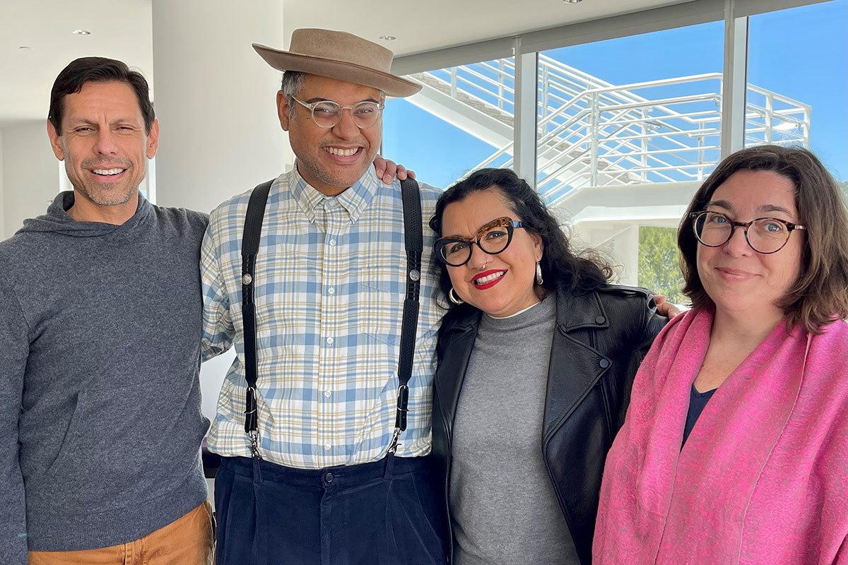 Four people pose arm in arm, smiling. 