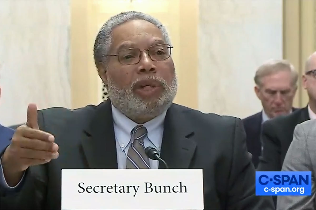 A man in a suit gestures while speaking into a microphone. The namecard in front of him reads Secretary Bunch, and a C-SPAN logo is in the bottom right corner.