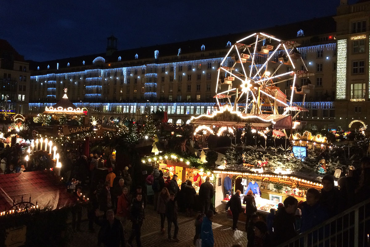 Outdoor market lit up at night, including a small Ferris wheel.