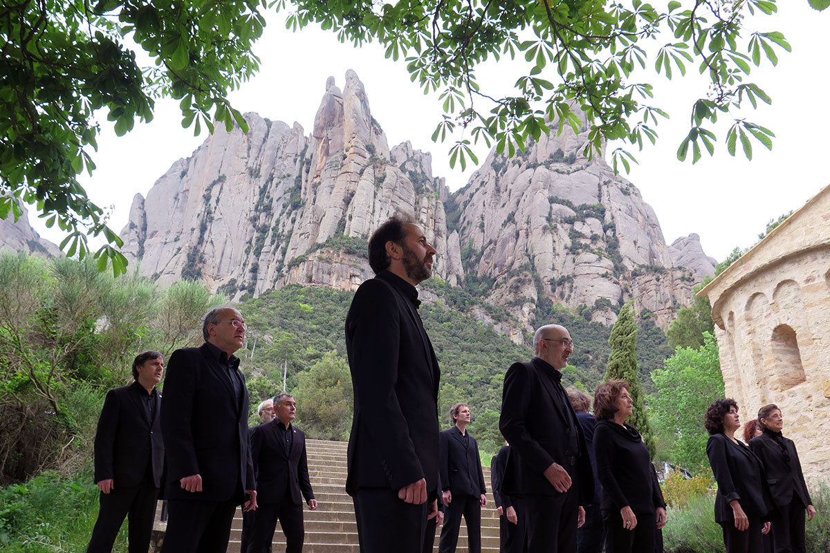 Several men and women dressed in all black, standing in formation with a towering stone mountain behind them.