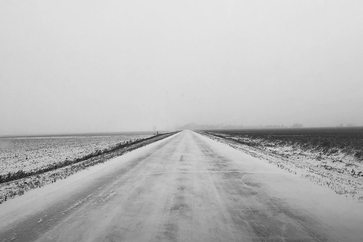 Barren landscape, road and prairie covered in snow.