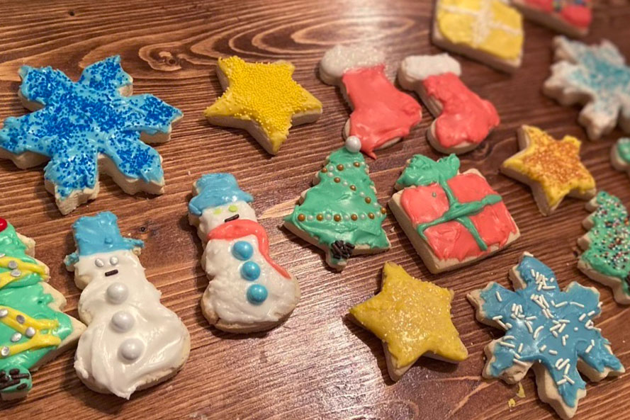 Cookies arranged on a countertop, decorated as snowflakes, stars, snowmen, stockings, presents, and Christmas trees.