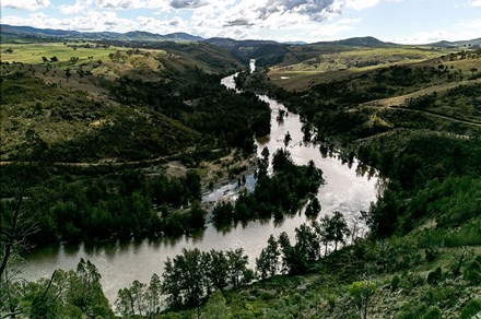 Silvery river curving through green hills.