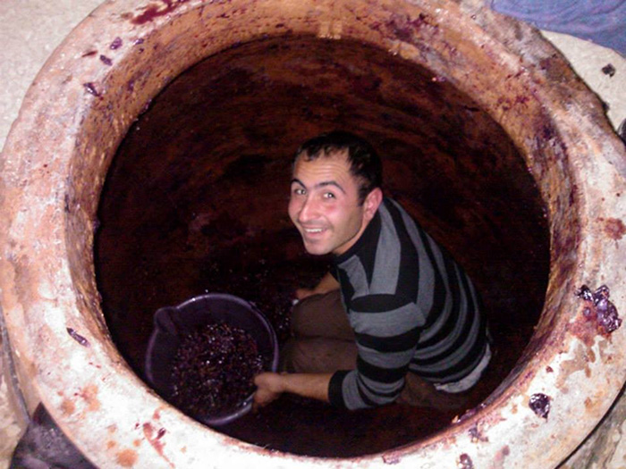 Alik Avetisyan crouches inside a 260-gallon karas, filling it with newly harvested grapes.